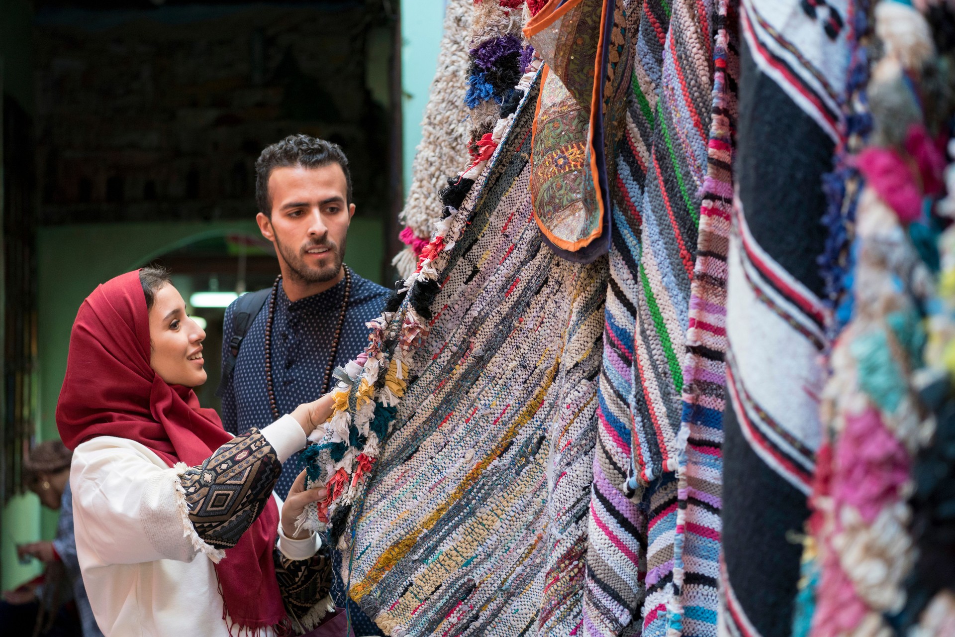 Smiling young muslim couple shopping carpets in a textile store