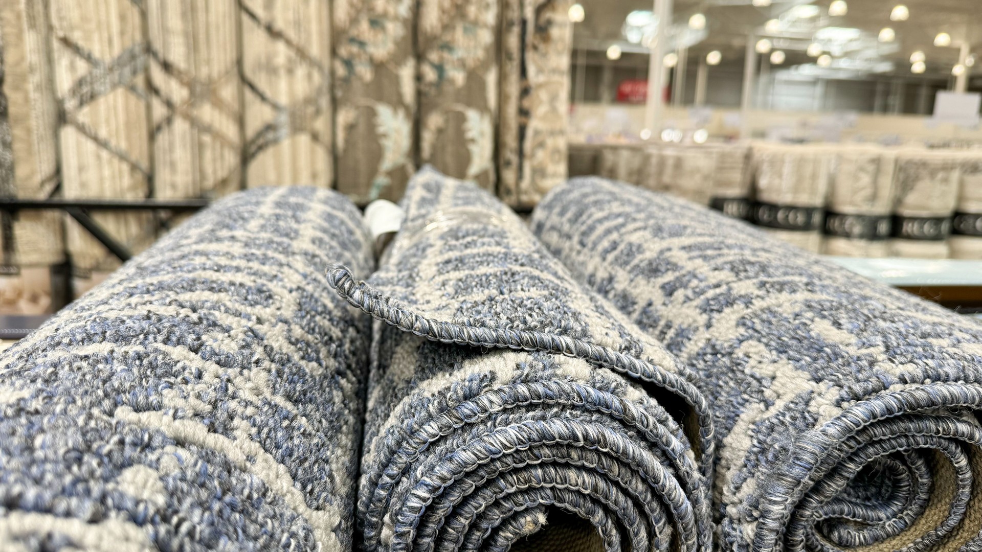 a close-up of rolled carpets with intricate patterns displayed in a store