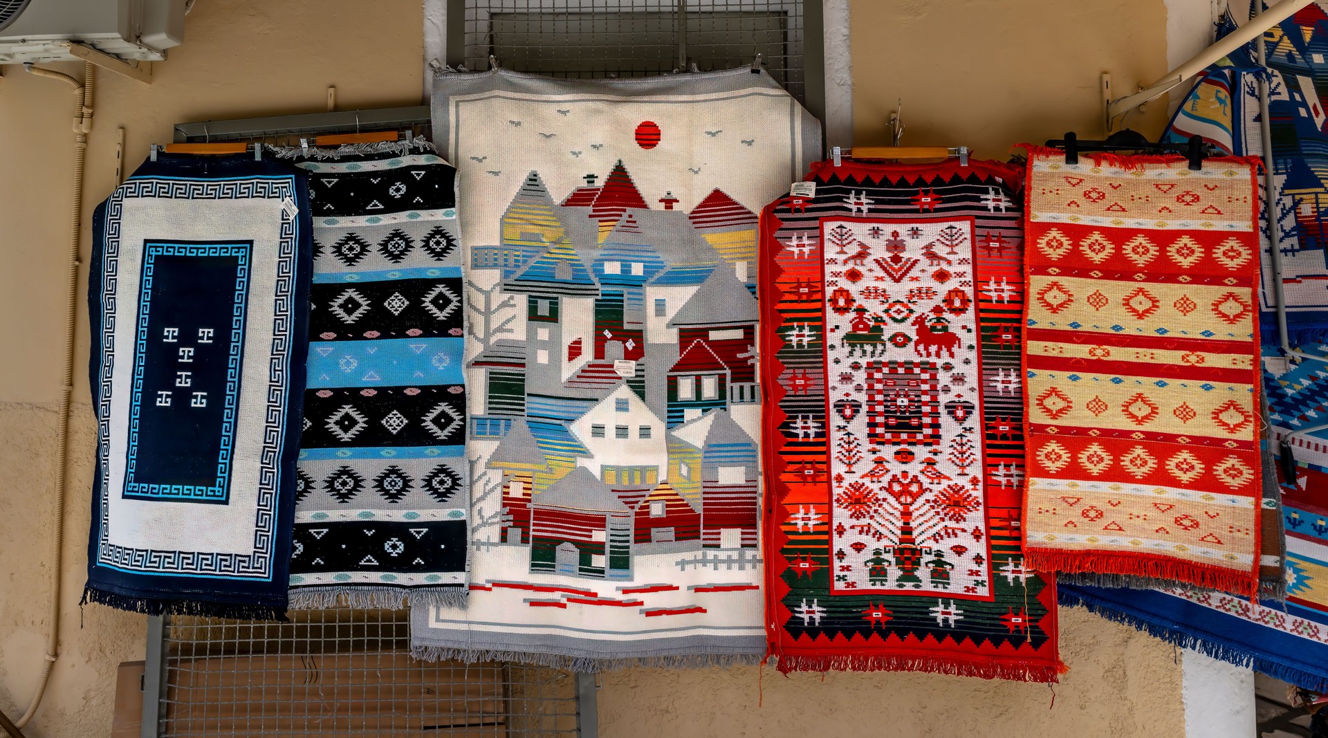 Colorful Assortment of Traditional Woven Rugs Hanging on Display Outdoors